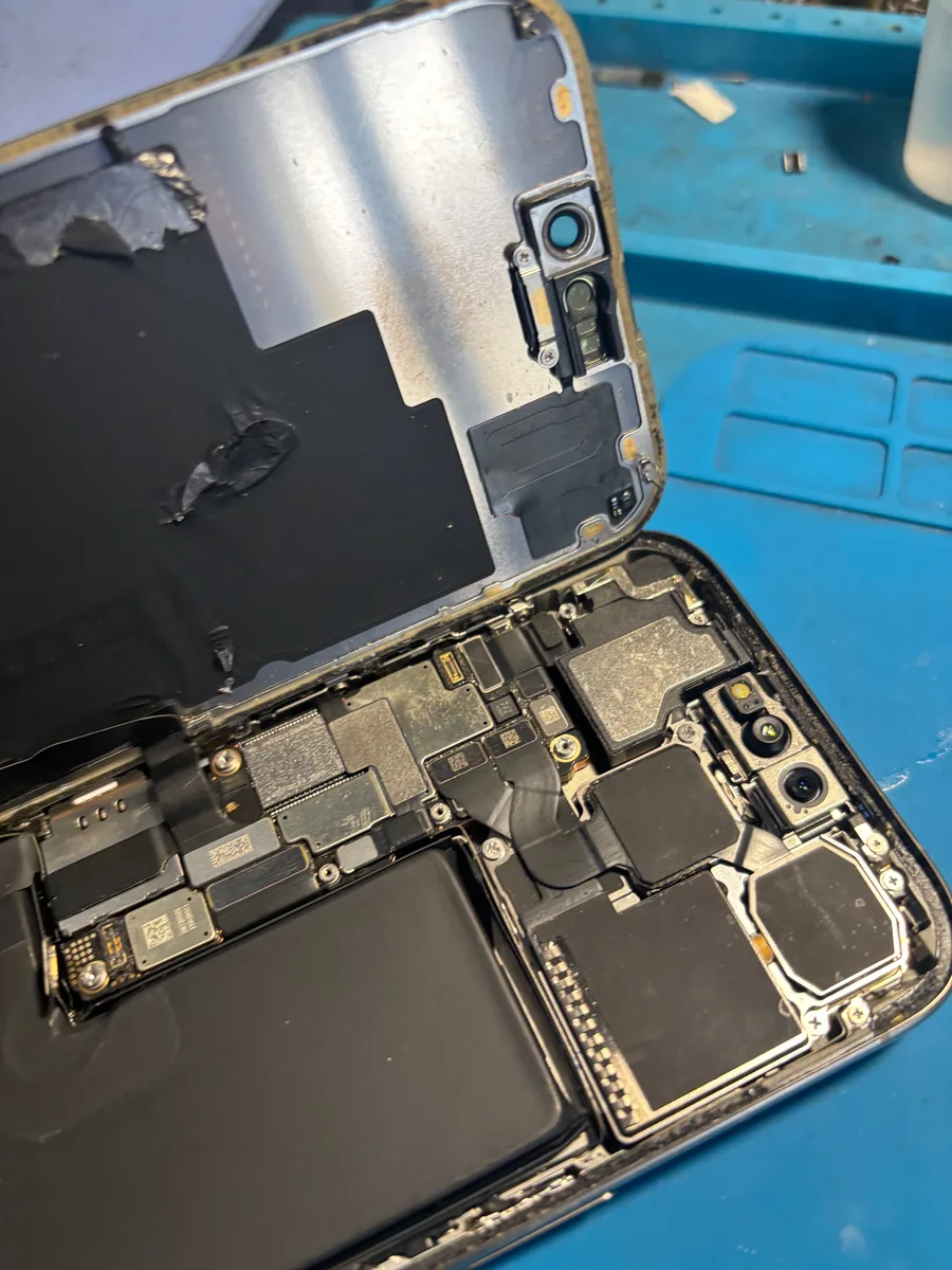 Dettaglio di iPhone smontato con vetro posteriore scheggiato e componenti interni in vista