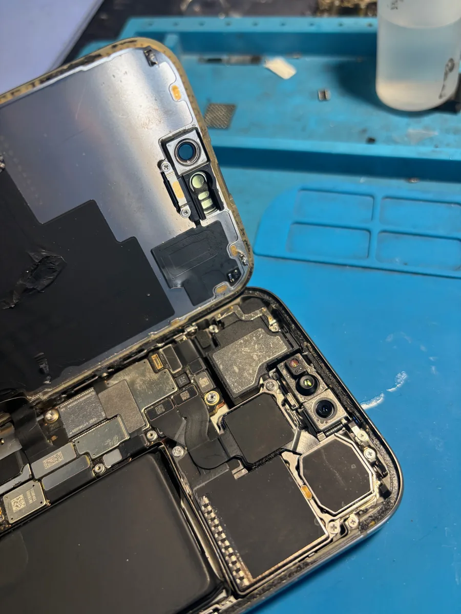 iPhone aperto in laboratorio con componenti interni a vista durante la sostituzione del vetro posteriore
