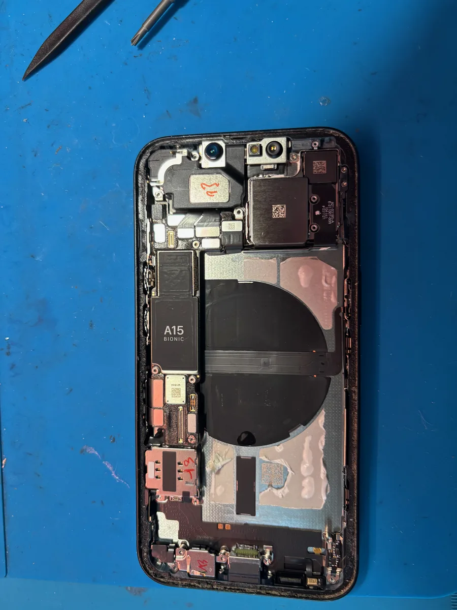 Telaio iPhone smontato sul tappetino da lavoro durante il rimontaggio della scocca posteriore