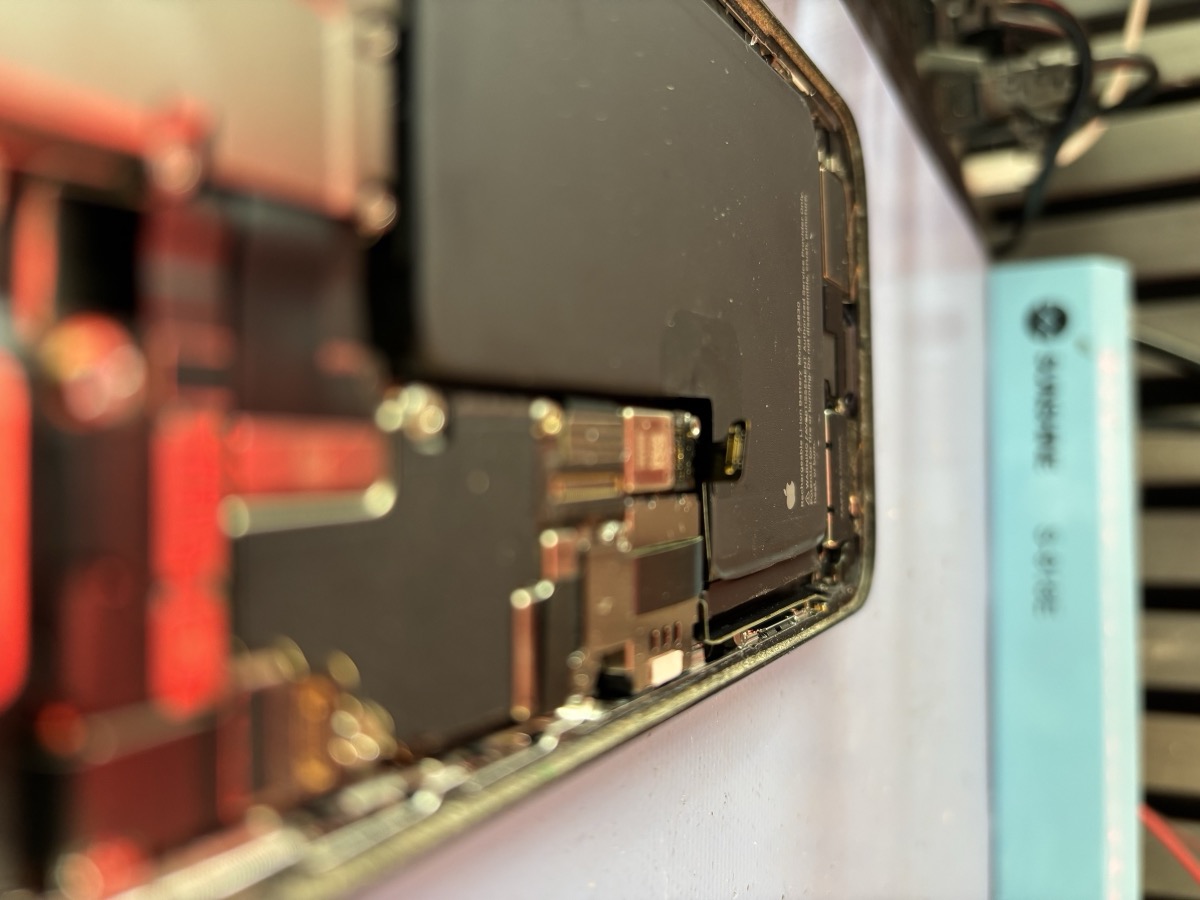 Dettaglio macro dei connettori flex interni di un iPhone 15 Pro durante la riparazione