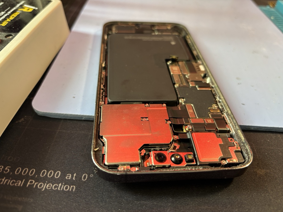 iPhone aperto con schermi EMI color rame visibili, batteria rimossa durante la riparazione a Torino
