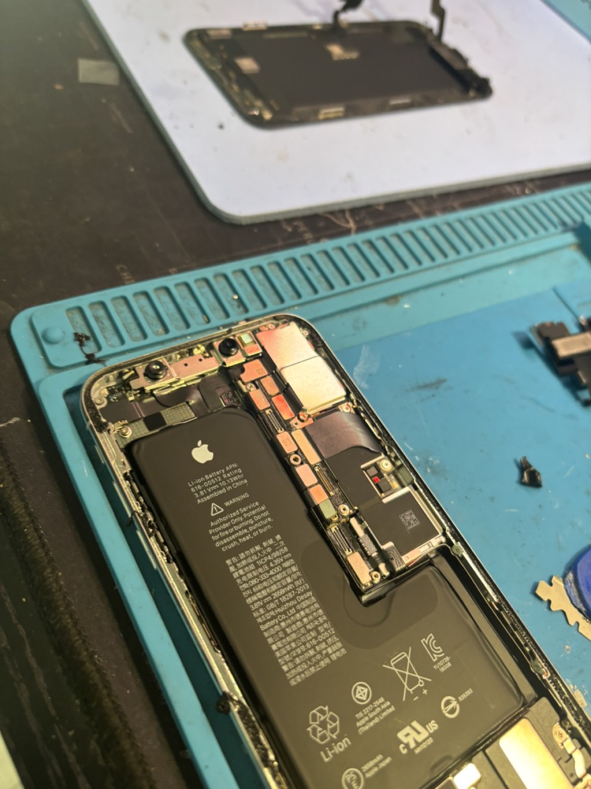 Scheda madre di iPhone 16 fissata sulla dima di microsaldatura nel laboratorio di Torino